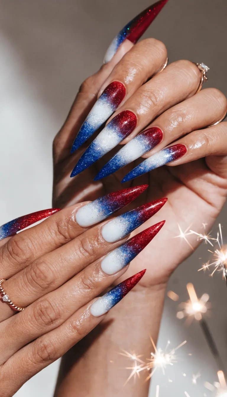Nails decorated with a red, white, and blue glitter gradient design for 4th of July celebrations.