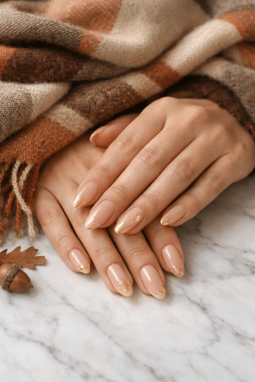 Nude almond nails with gold accents and a cozy plaid scarf