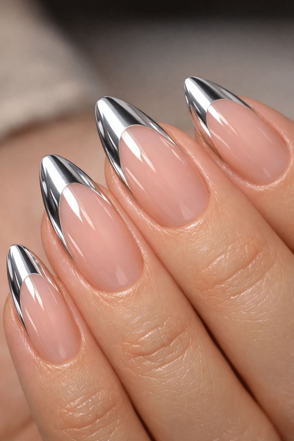 Close-up of milky pink almond nails with reflective chrome tips.