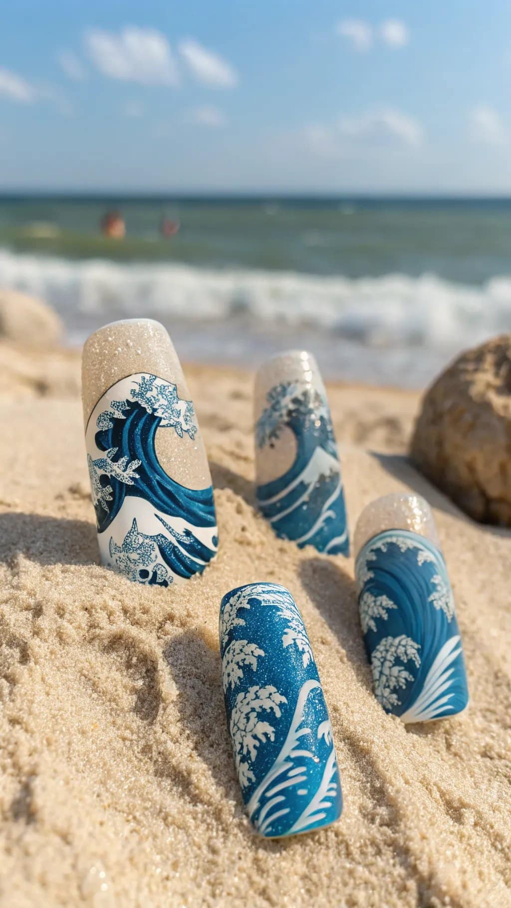 9 Trendy Summer Nail Designs for 2026 3 Ocean-inspired nail designs showing blue waves and sandy texture on a beach.