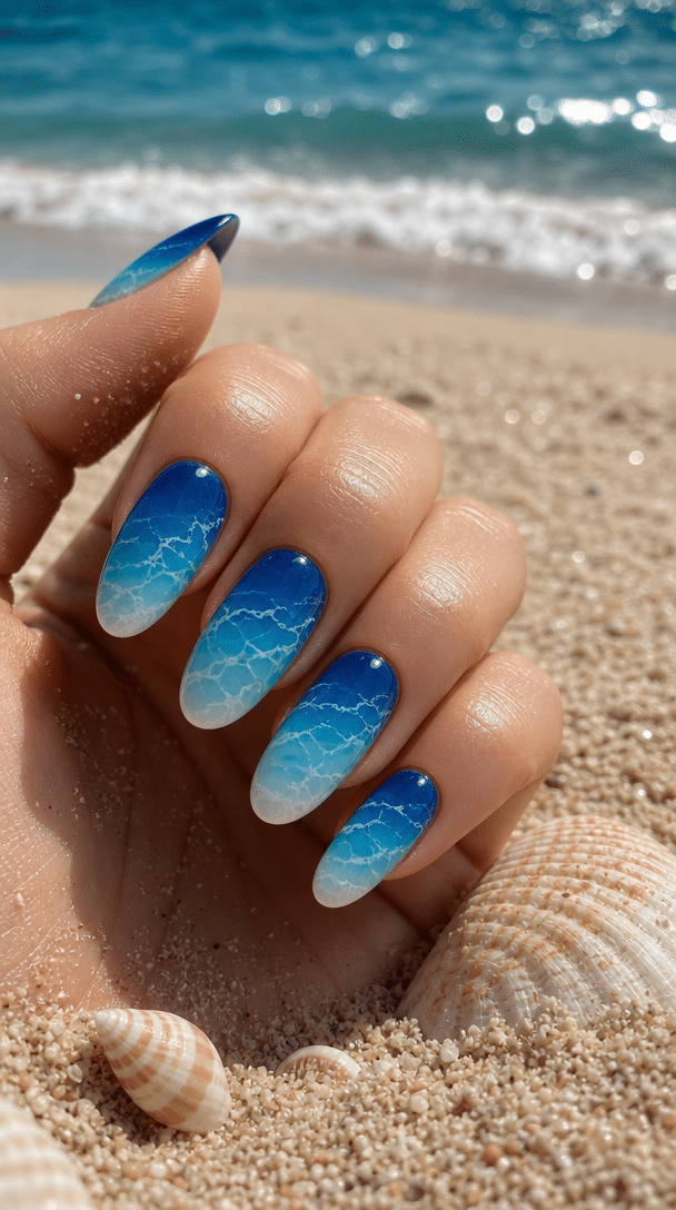 Close-up of ocean wave ombre nails showing various shades of blue.