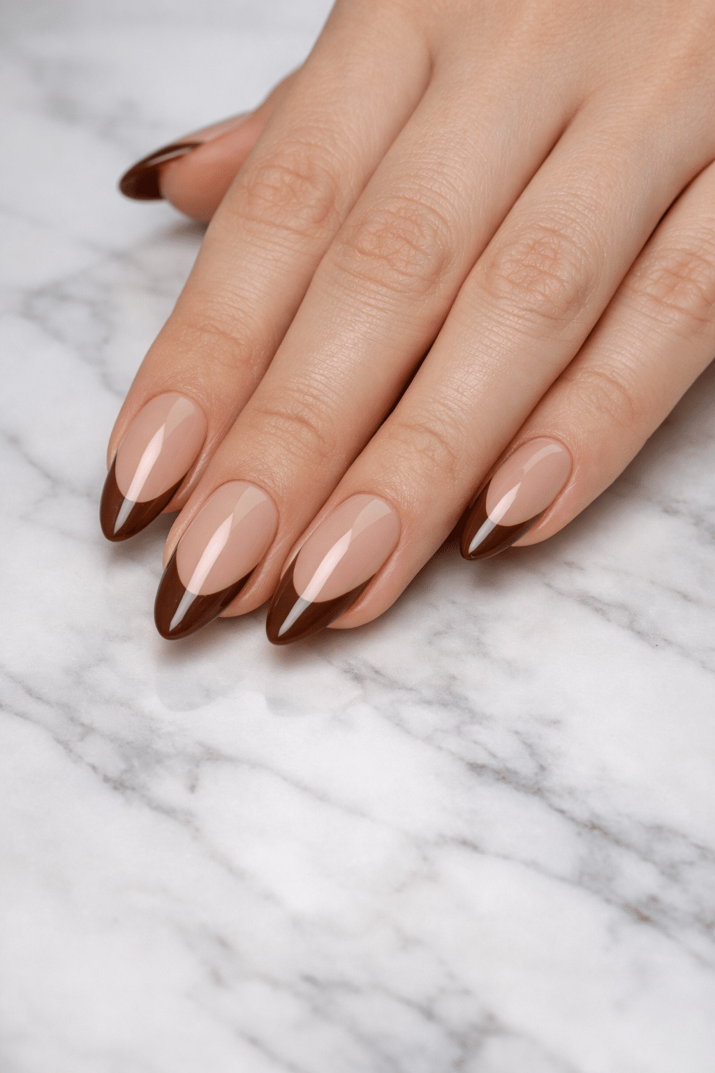 Classic almond-shaped nails with brown tips on a marble surface