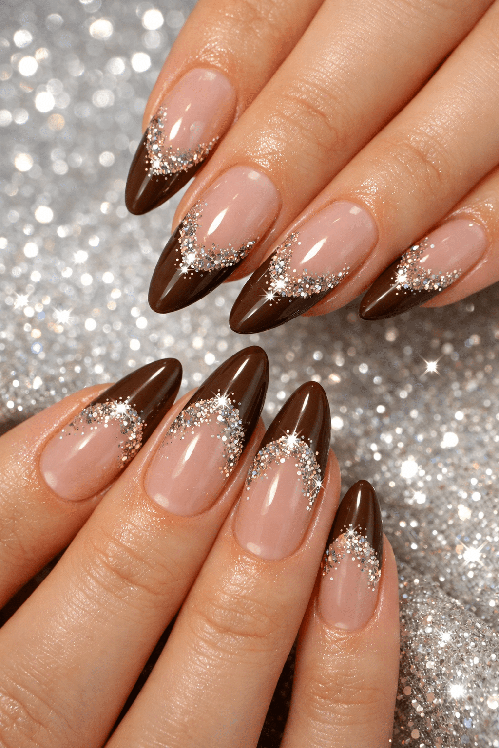 Almond-shaped nails with brown French tips and glitter accents.