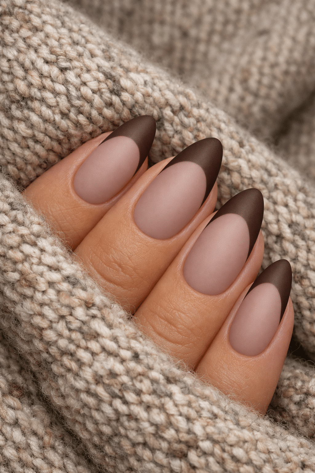 Matte finish almond nails with a brown French tip on a textured background