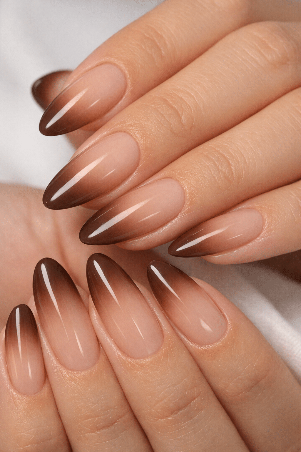 Almond nails featuring a beautiful caramel and nude ombre effect, showing a seamless gradient.