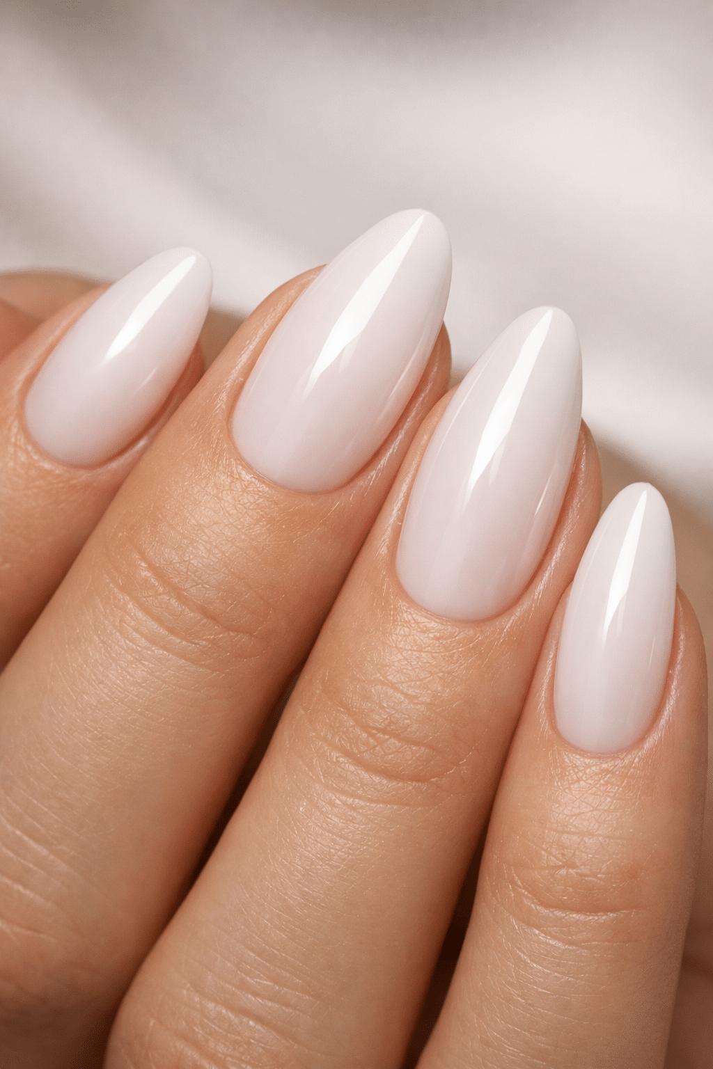 Close-up of short almond-shaped nails in a milky white finish.